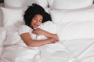 Photo of Beautiful young woman sleeping in soft bed, above view