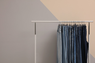 Rack with stylish jeans near color wall