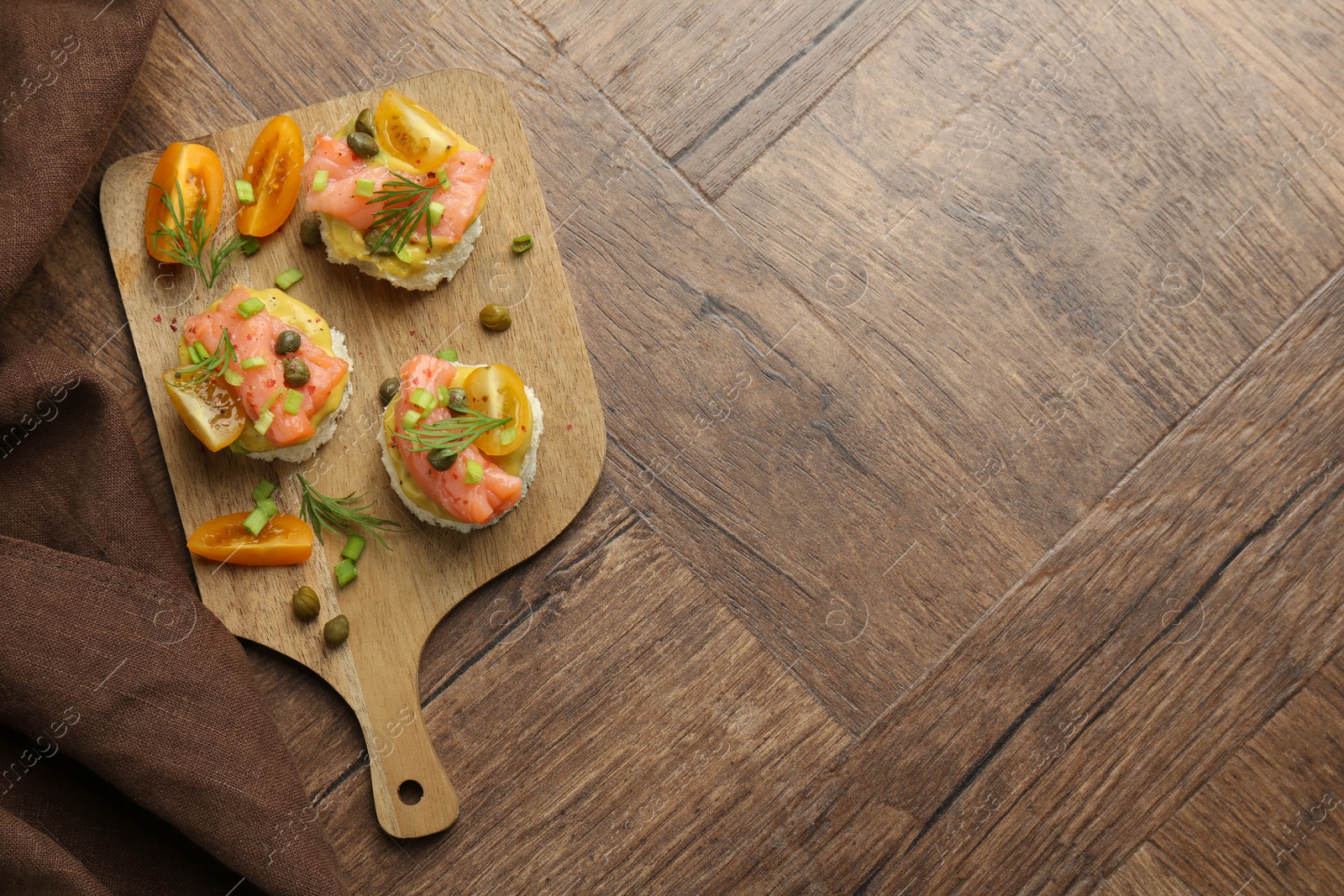 Photo of Tasty canapes with salmon served on wooden table, top view. Space for text