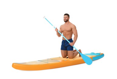 Handsome man with paddle on orange SUP board against white background