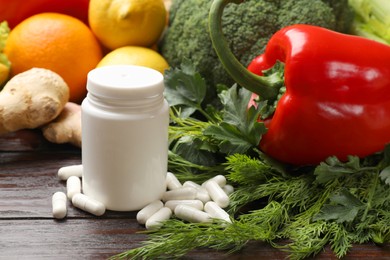 Photo of Dietary supplements. Plastic bottle, pills and food products on wooden table