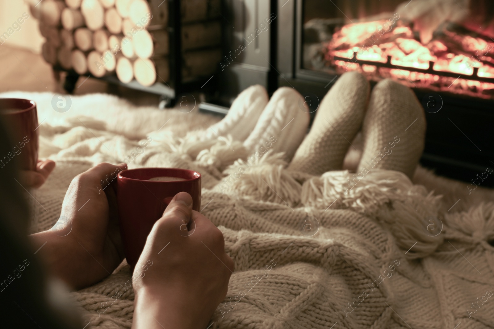 Photo of Couple in knitted socks near fireplace at home, closeup