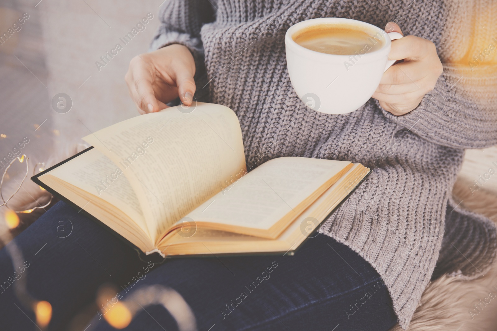 Image of Woman with cup of coffee reading book at home, closeup