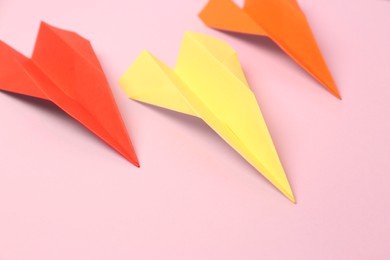 Photo of Colorful handmade paper planes on pink background, closeup