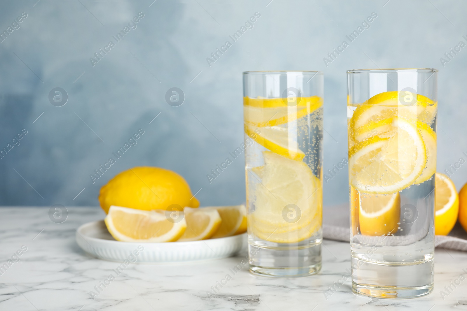 Photo of Soda water with lemon slices on white marble table. Space for text