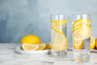 Soda water with lemon slices on white marble table. Space for text