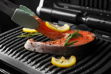 Photo of Cooking salmon. Grill with fresh fish steak, lemon and rosemary