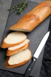 Photo of Cut tasty baguette with knife on grey table, flat lay