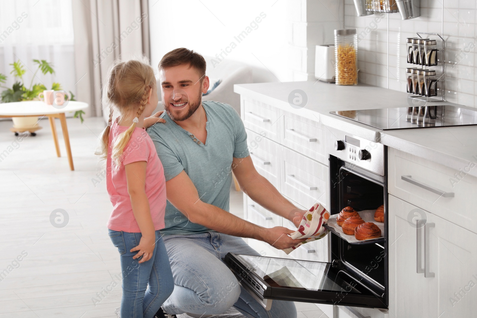 Photo of Father and daughter taking out buns from oven in kitchen