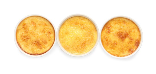 Photo of Delicious creme brulee in ceramic ramekins on white background, top view