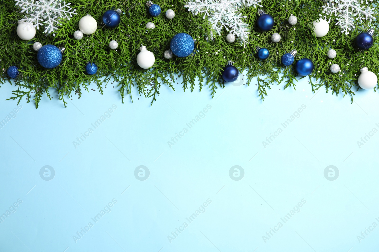 Photo of Fir tree branches with Christmas decoration on light blue background, flat lay. Space for text