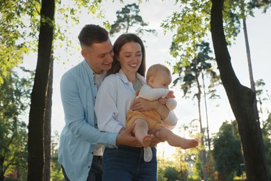 Parents with their cute daughter spending time together in park on summer day