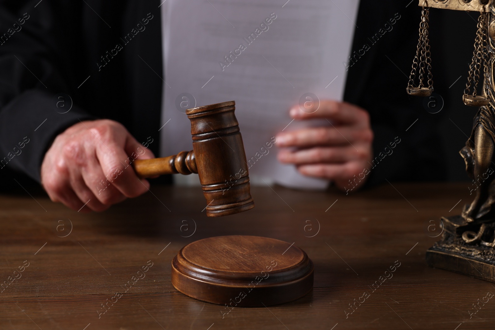 Photo of Judge with gavel sitting at wooden table, closeup