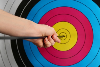 Photo of Woman pulling out arrow from archery target, closeup