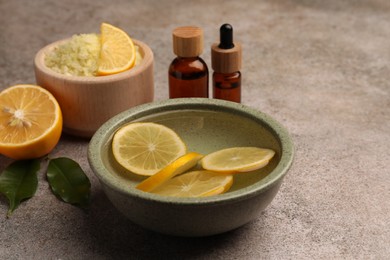 Photo of Essential oil with lemons and sea salt on grey textured table. Aromatherapy treatment