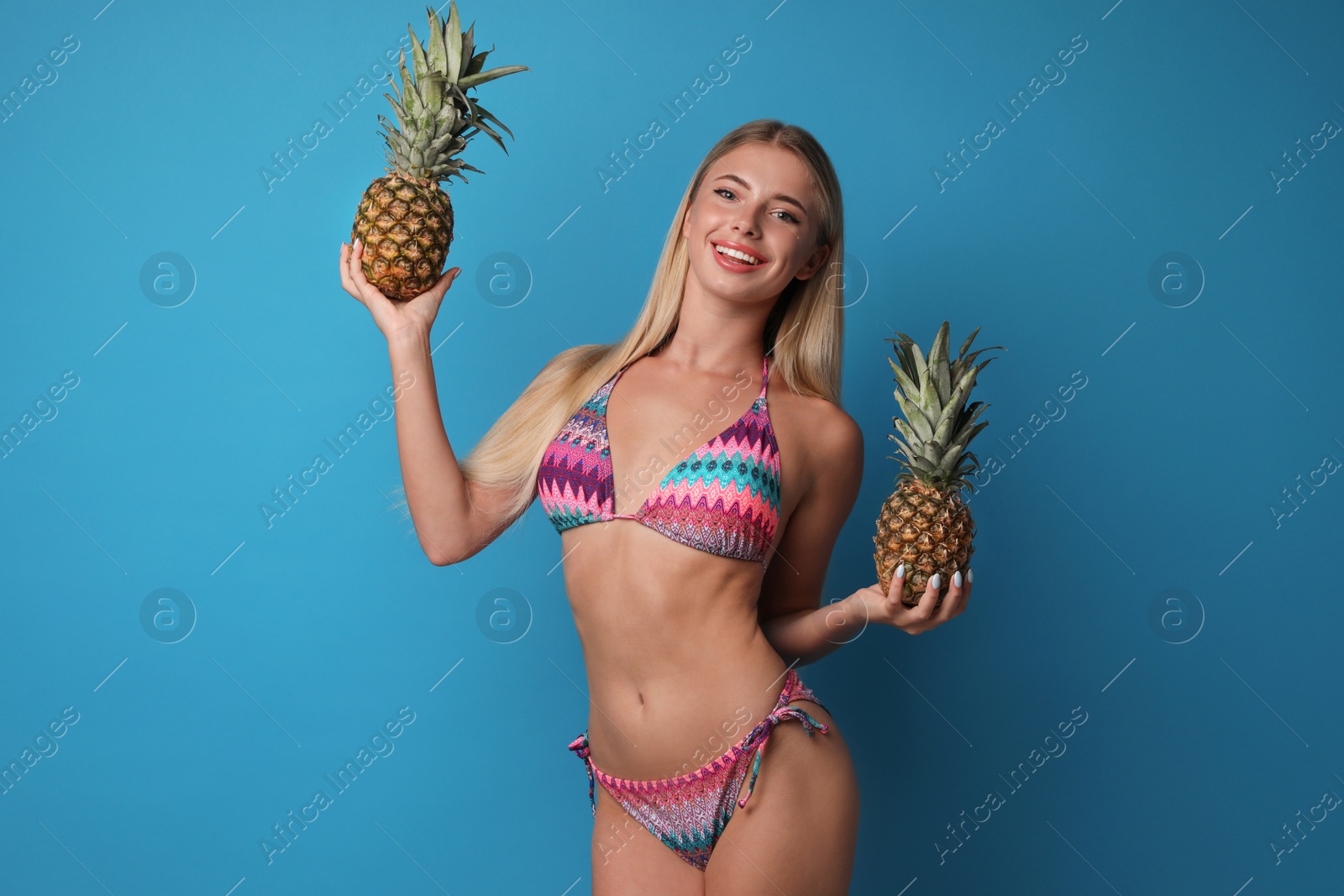 Photo of Pretty young woman wearing stylish bikini with pineapples on blue background