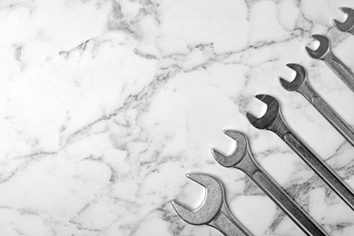 New wrenches on marble background, top view with space for text. Plumber tools