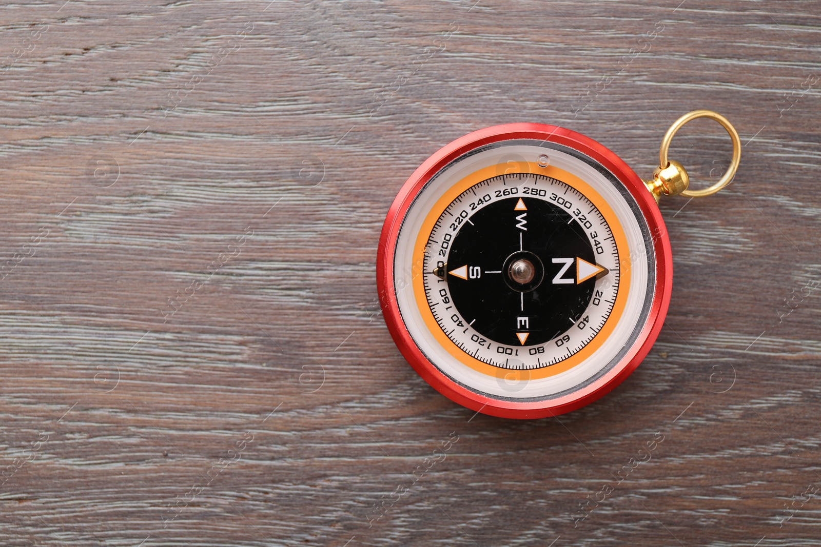 Photo of One compass on wooden table, top view. Space for text