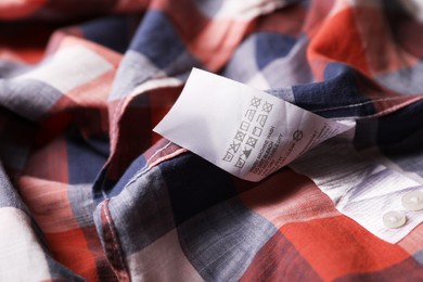 Clothing label on beautiful checkered garment, closeup
