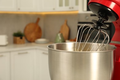 Photo of Modern red stand mixer with cream in kitchen, closeup. Space for text