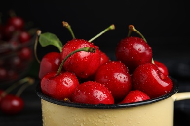 Metal mug with ripe sweet cherries on dark background, closeup