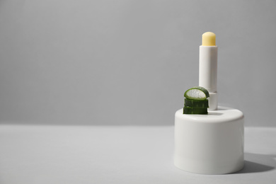 Hygienic lipstick and cut aloe vera leaf on light table. Space for text