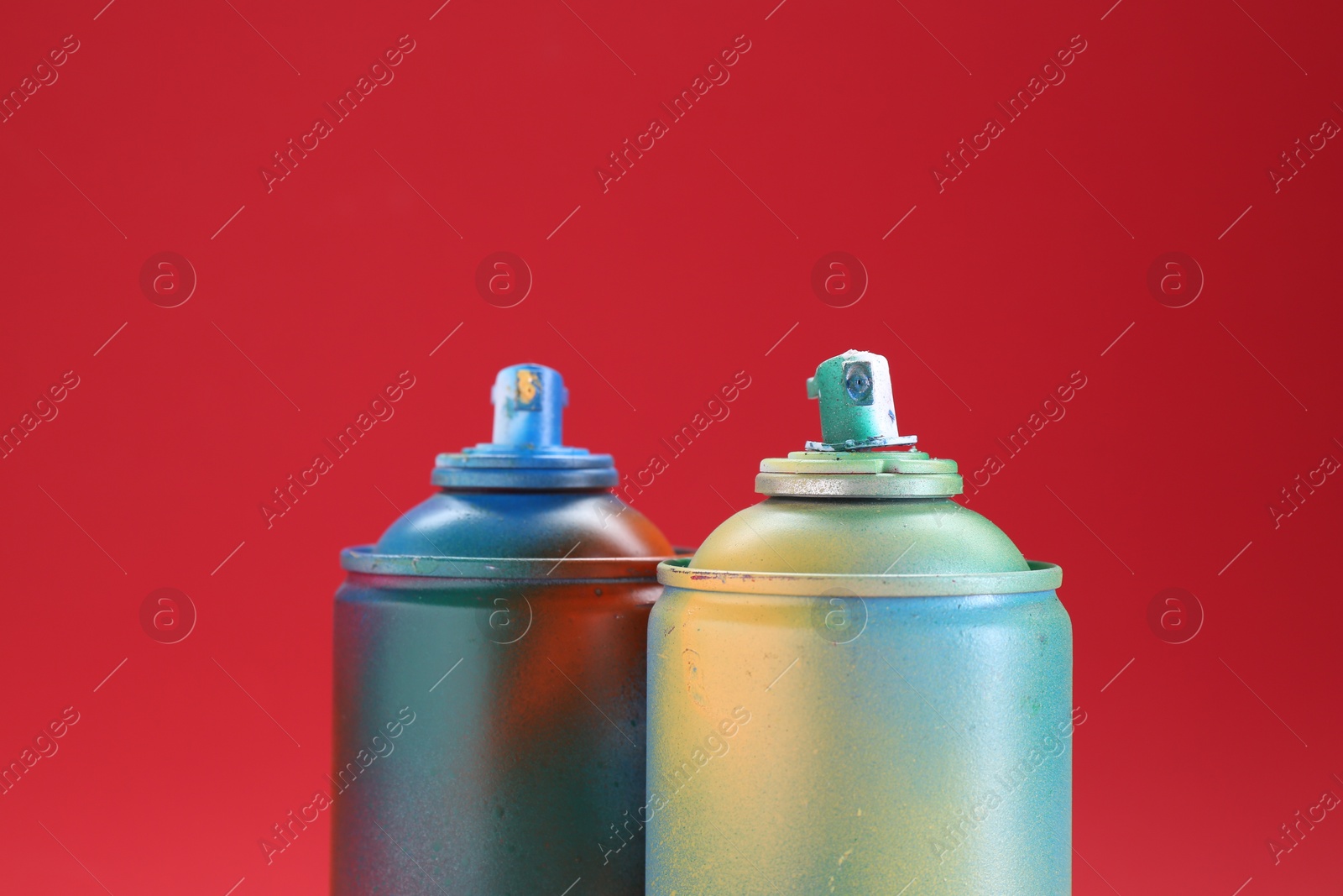 Photo of Two spray paint cans on red background