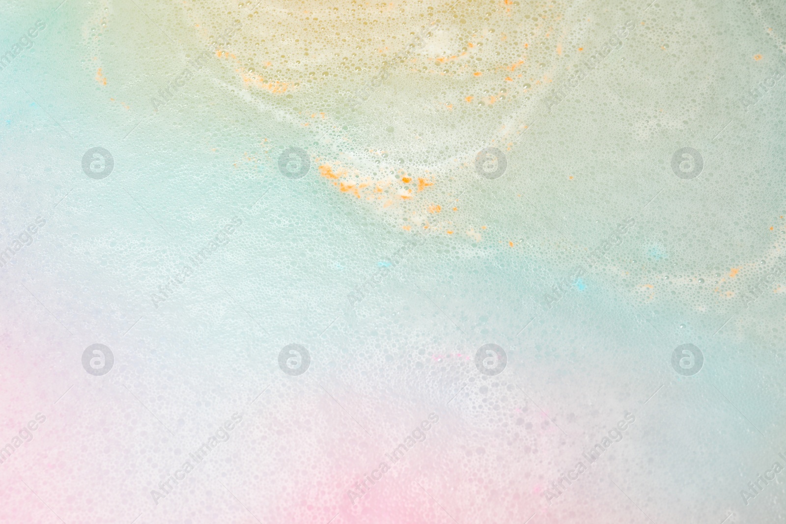 Photo of Colorful foam after dissolving bath bomb in water, closeup