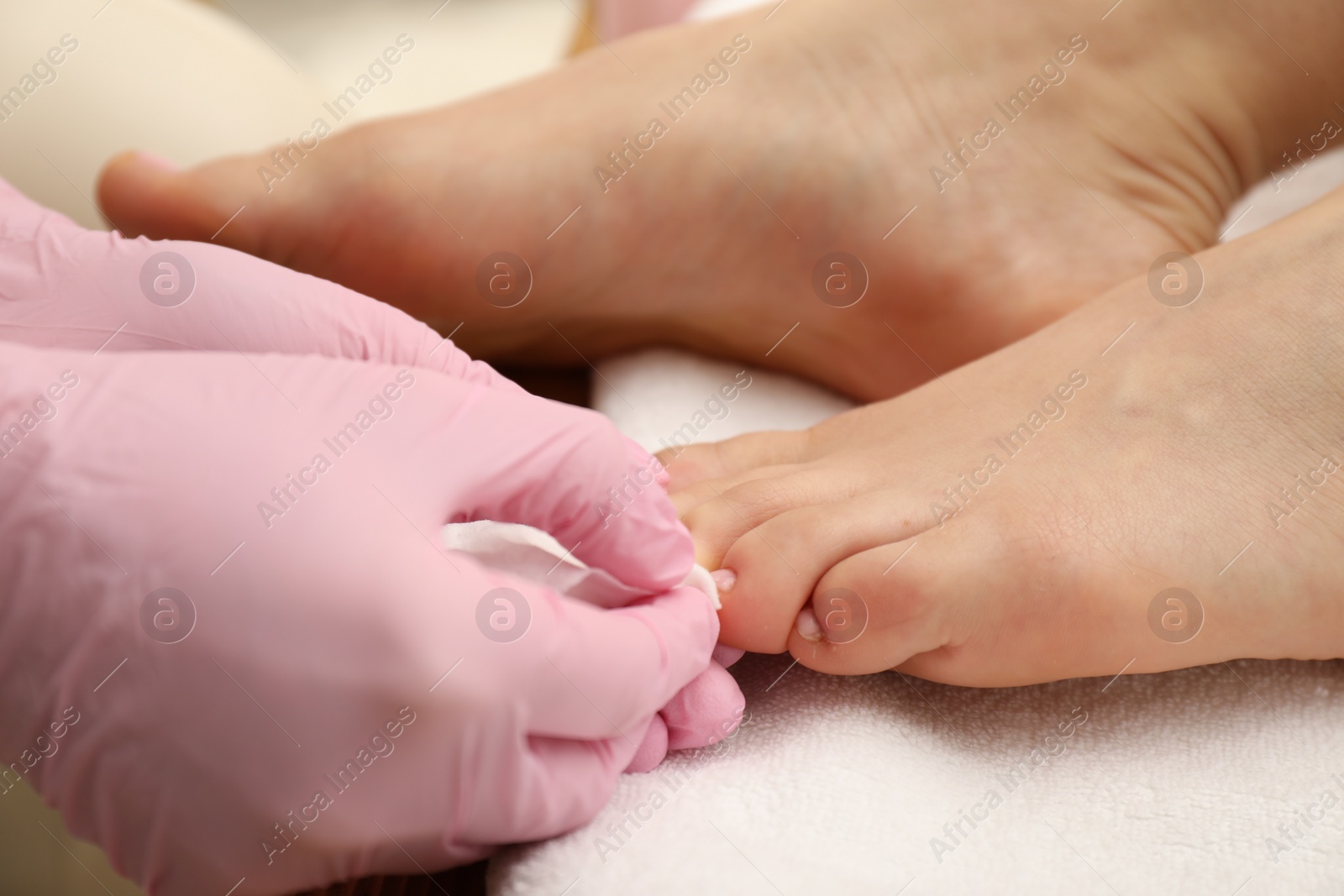 Photo of Professional pedicurist working with client`s toenails in beauty salon, closeup
