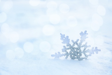 Image of Beautiful decorative snowflake on white snow. Space for text