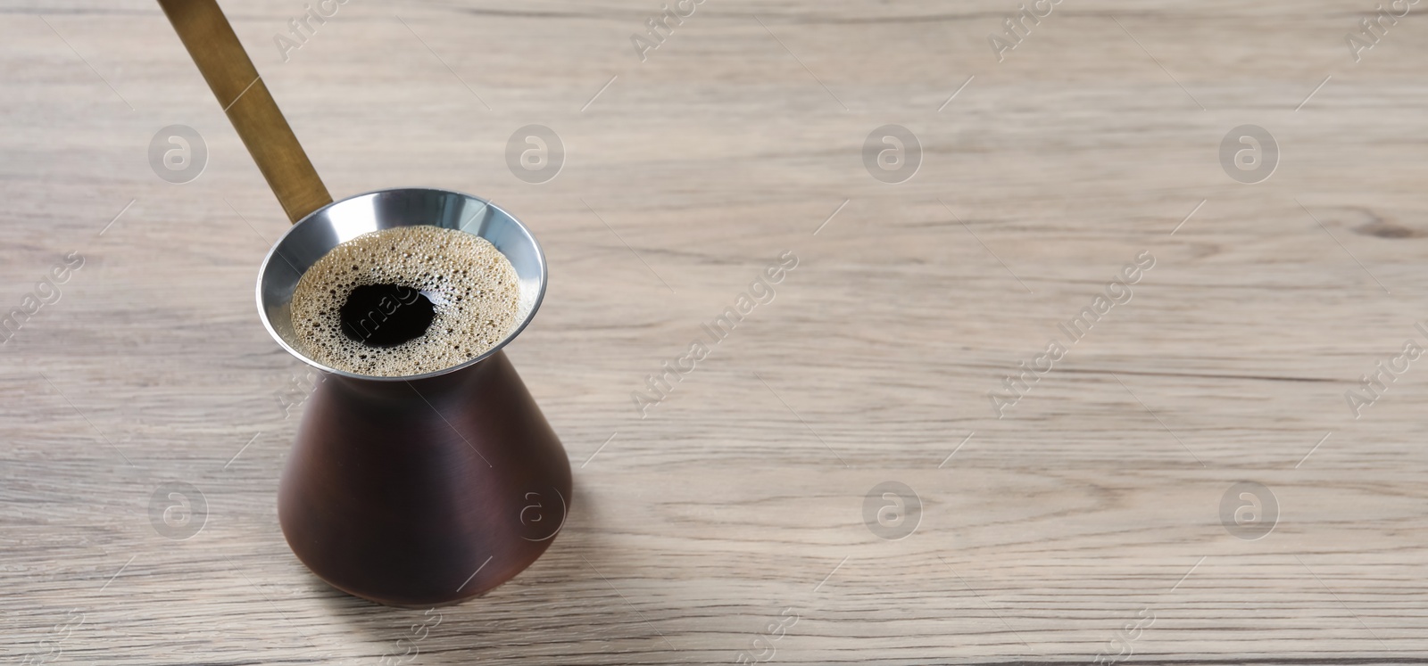 Image of Turkish coffee. Cezve on wooden table. Banner design with space for text