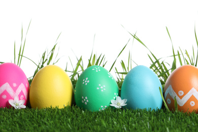 Colorful Easter eggs and flowers on green grass against white background