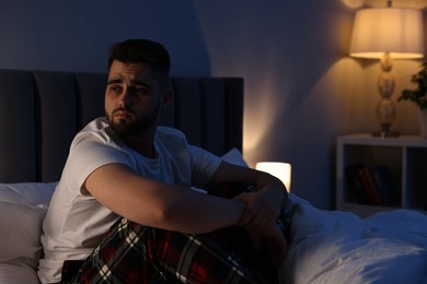 Photo of Frustrated man suffering from insomnia on bed