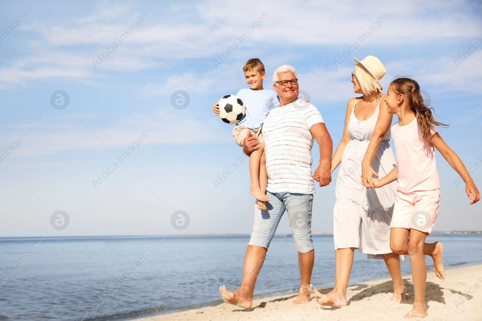 Photo of Cute little children with grandparents spending time together on sea beach