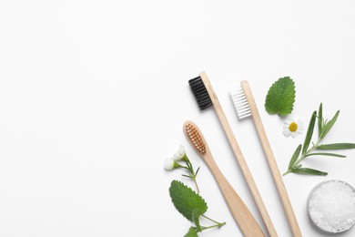 Photo of Bamboo toothbrushes, flowers, herbs and sea salt on white background, flat lay. Space for text
