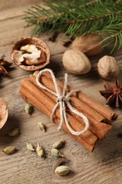 Photo of Different spices, nuts and fir branches on wooden table, above view