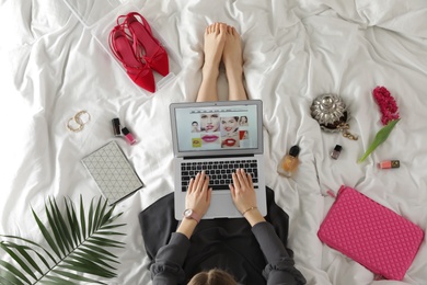 Photo of Woman and laptop with beauty blogger site on bed, top view