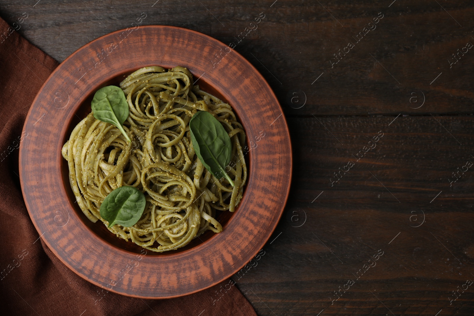 Photo of Tasty pasta with spinach on wooden table, top view. Space for text