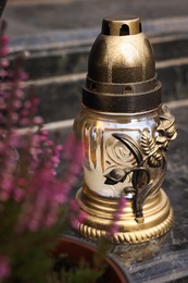 Photo of Grave lantern with candle on granite surface at cemetery