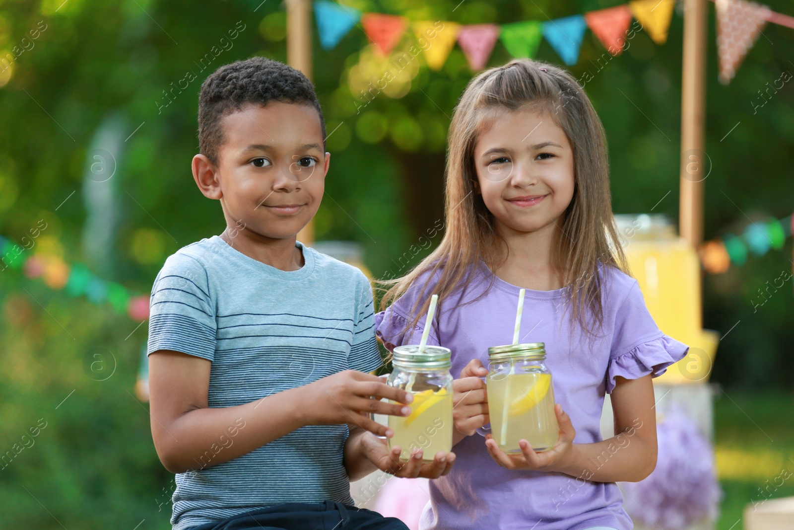 Photo of Cute little children with natural lemonade in park. Summer refreshing drink