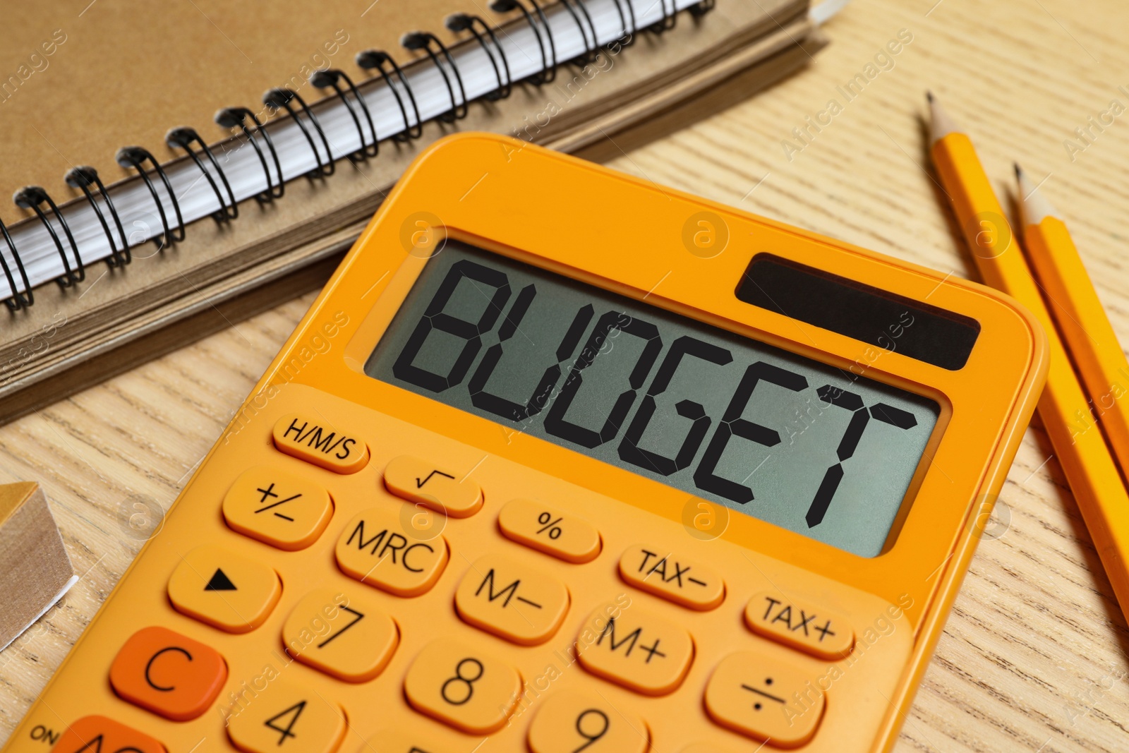 Image of Calculator with word Budget, notebook and pencils on wooden table, closeup