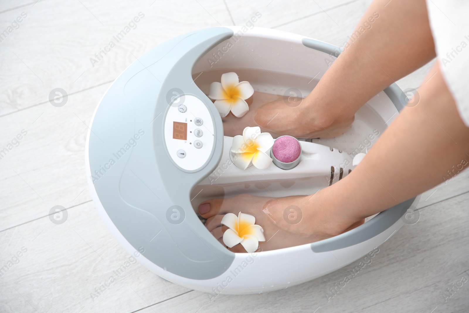 Photo of Woman with beautiful legs using foot bath at home, closeup. Spa treatment