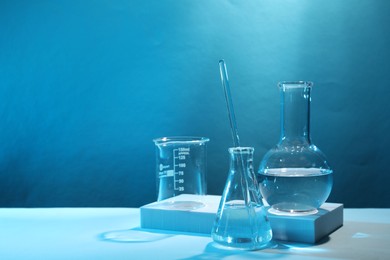 Photo of Laboratory analysis. Different glassware on table against light blue background, space for text