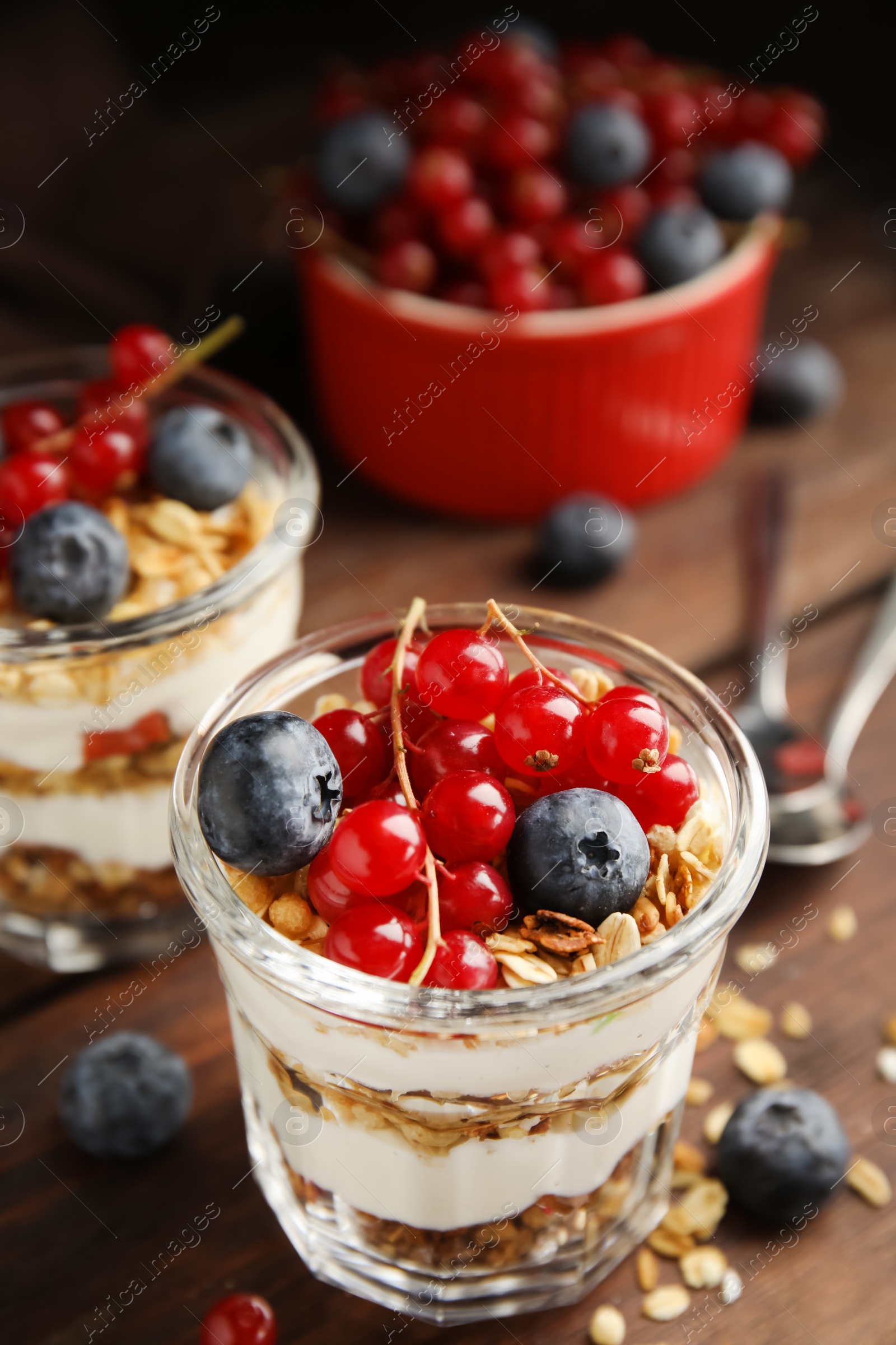 Photo of Delicious yogurt parfait with fresh berries on wooden table, closeup