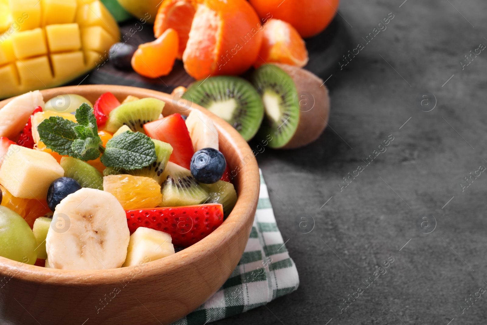 Photo of Delicious fresh fruit salad on grey table, space for text