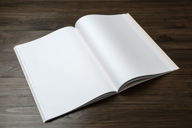 Photo of Open blank paper brochure on wooden table. Mockup for design