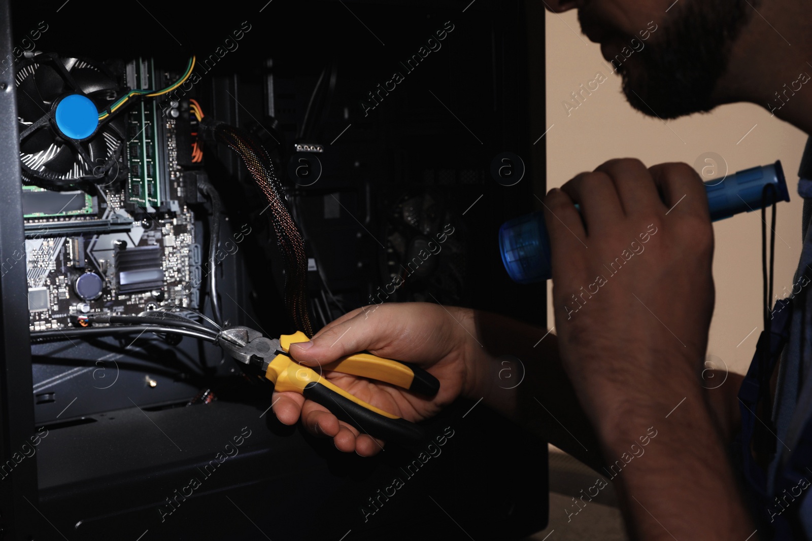 Photo of Man with flashlight fixing system unit indoors, closeup