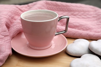 Cup of tasty cocoa, pink sweater and cookies on wooden table