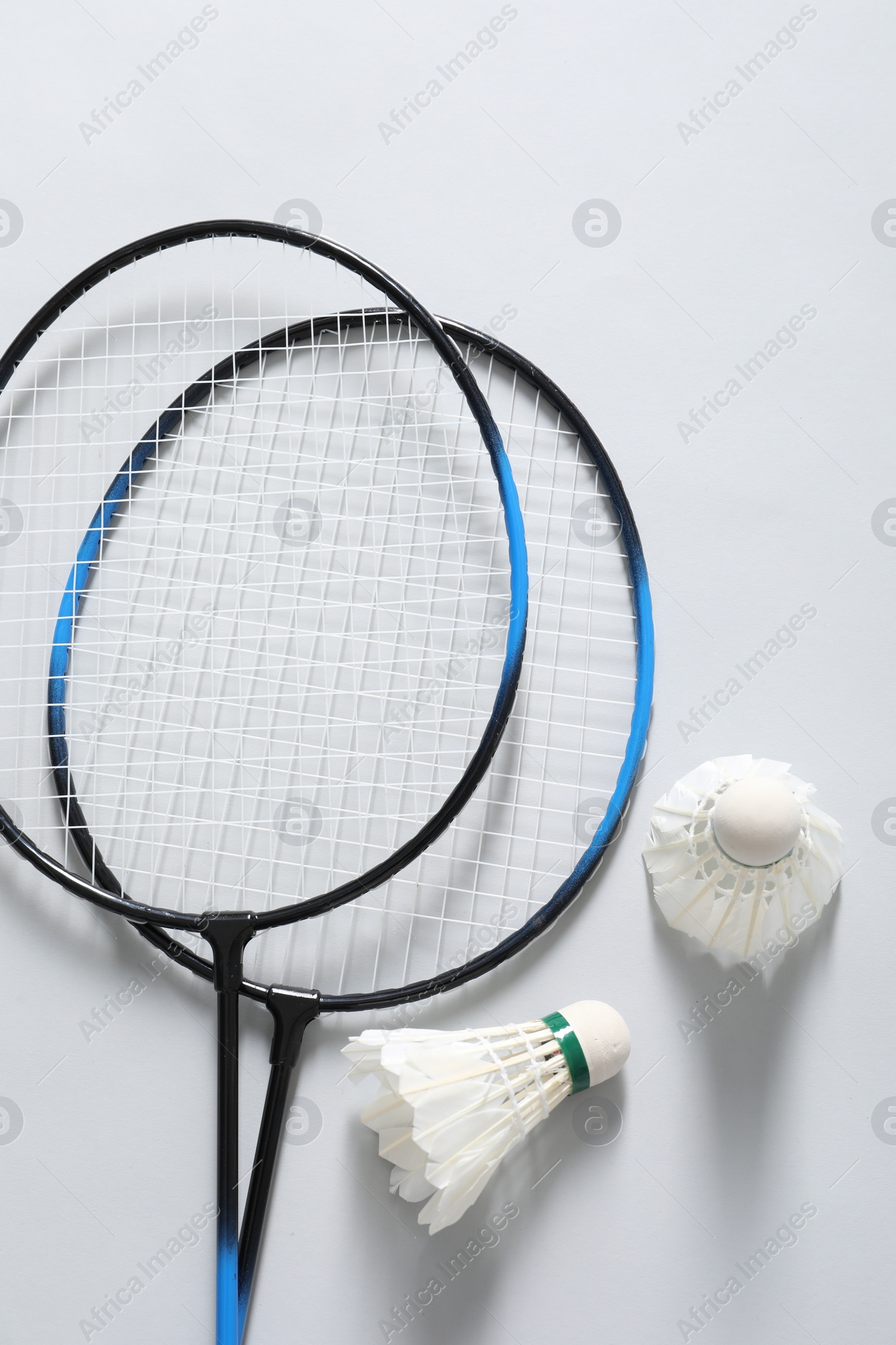 Photo of Feather badminton shuttlecocks and rackets on gray background, flat lay