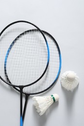 Feather badminton shuttlecocks and rackets on gray background, flat lay